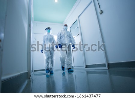 Researchers in protective clothing walking through laboratory hall. Virus and diseases safety concept Royalty-Free Stock Photo #1661437477