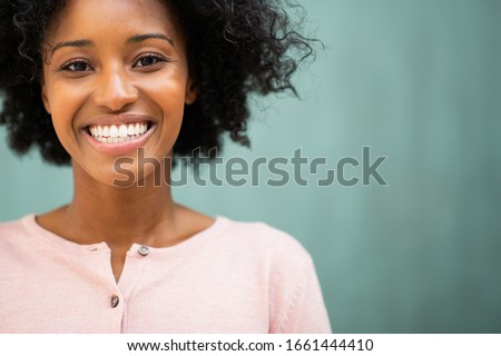 Close up portrait beautiful young black woman smiling by green background