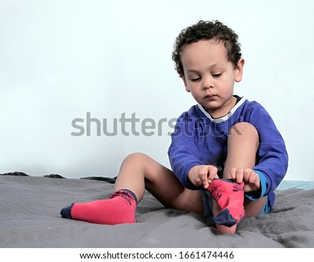 boy putting his socks on in bed stock photo 