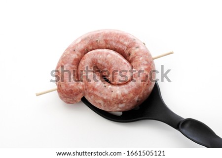 Rolled, raw bratwurst on spatula