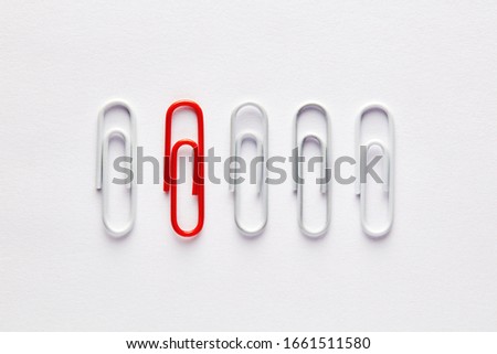 Red paper clip stands out from the crowd. Concept of difference, extraordinary or diverse.