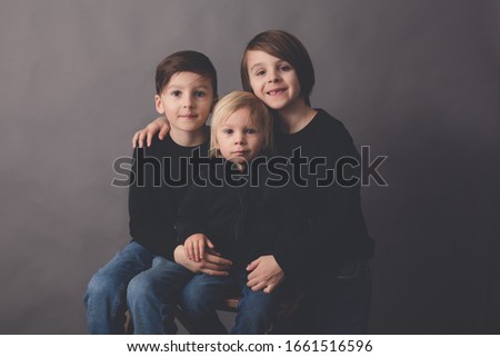 Sweet children, boy brothers in black sweater, listening music, isolated background