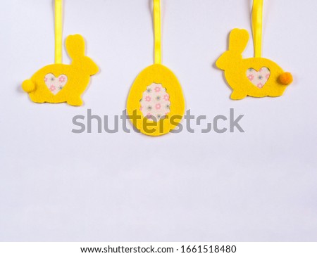 Yellow felt easter bunny figurine with heart-shaped applique on a white background