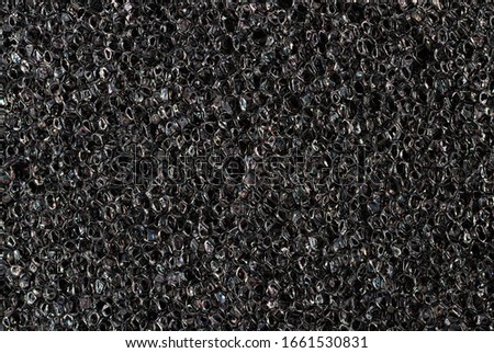 Black sponge texture close up. High quality macro texture of foam rubber.