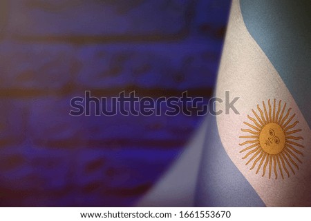 Argentina hanging flag for honour of veterans day or memorial day on blue blurred painted brick wall background. Argentina glory to the heroes of war concept.