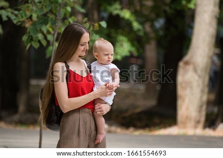 Young beautiful mother holding baby over Park background. Walk with child. Lifestyle.