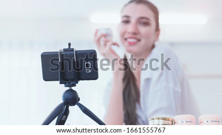 Beautiful woman beauty vlogger blogger recording live make up tutorial share on social media using digital camera on tripod.