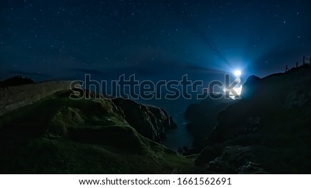 Beams of light shining from Fanad Head Lighthouse at dark night with sky full of stars. Long exposure photography. Wild Atlantic Way, Donegal, Ireland
