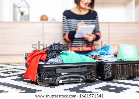 Beautiful young woman packing her stuff into a big suitcase. Traveling preparation concept.  Royalty-Free Stock Photo #1661571541