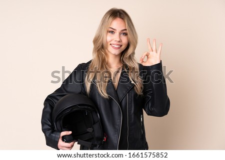 Russian girl with a motorcycle helmet isolated on beige background showing ok sign with fingers