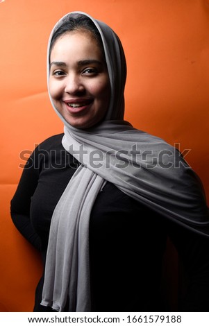 Portrait of happy Arabic girl wearing Hijab on orange background,beautiful Middle Eastern girl in Arabic Traditional Abbaya 