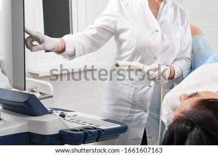 gynecologist holding transvaginal ultrasound wand after examining a woman and showing results on a screen Royalty-Free Stock Photo #1661607163