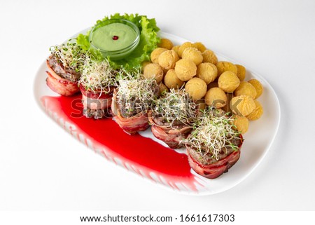 Beef minion in bacon with herbs in berry sauce with potatoes. Banquet festive dishes. Gourmet restaurant menu. White background.