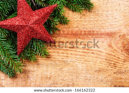 Christmas Border with Fir Tree Branch and Christmas decoration on wooden background. Vintage christmas background with red star.