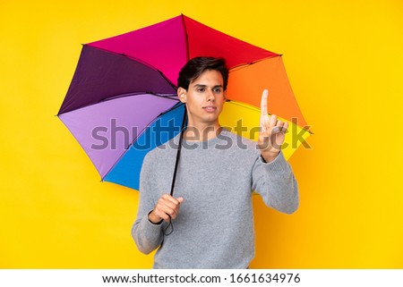 Man holding an umbrella over isolated yellow background touching on transparent screen