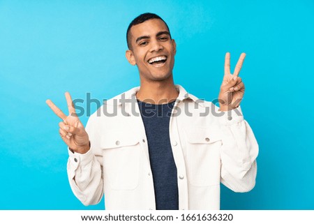 Young African American man over isolated blue background showing victory sign with both hands