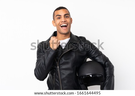 Young handsome man with a motorcycle helmet over isolated white background celebrating a victory