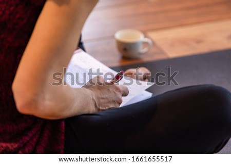 The unrecognizable female studying hard and making notes on a pad. The girl doing homework sitting on the floor. A making notes woman Royalty-Free Stock Photo #1661655517