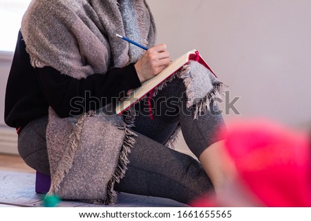 Unrecognizable woman studying yoga. A female making notes. Medium shot. Elderly woman writing notes during the workshop in the yoga center Royalty-Free Stock Photo #1661655565