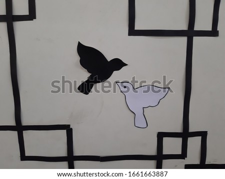 These are two pieces of bird pictures. Bird one is white and bird two is black. Both are posted on the wall.