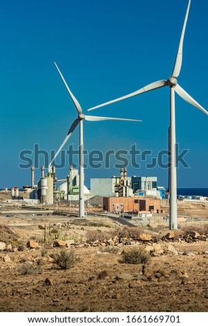 Thermal power station and a series of wind turbines near the sea coast. Wind farm eco field. Eolic park with blue sky in background. Green, ecological and power energy generation concept.