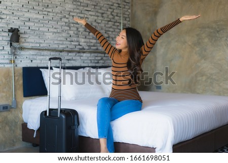 Young asian woman with luggage bag in bedroom interior