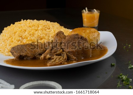 "Seco de Chivo" is a delicious tradition of Ecuador, served with rice, potatoes and hot sauce Royalty-Free Stock Photo #1661718064