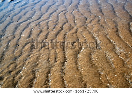 Natural sand patterns in beach at low tide.
