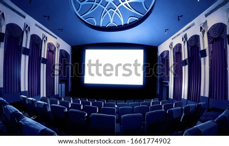 Cinema theater screen in front of seat rows in movie theater showing white screen projected from cinematograph. The cinema theater is decorated in classical style for luxury feeling of movie watching. Royalty-Free Stock Photo #1661774902