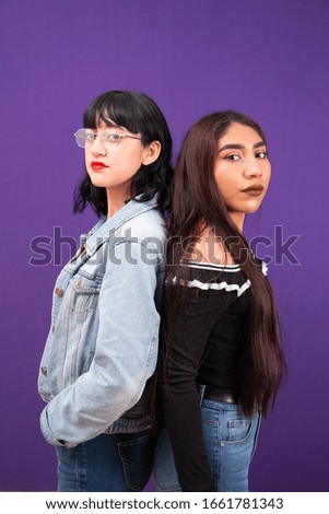 Two latin young ladies posing back to back