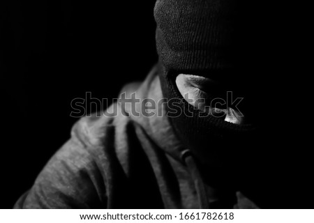 angry man in a balaclava on a dark background. Royalty-Free Stock Photo #1661782618
