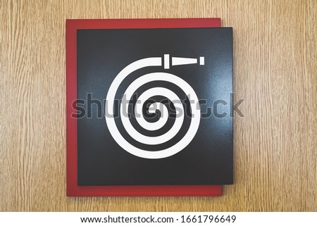 Fire hose sign icon on wood background