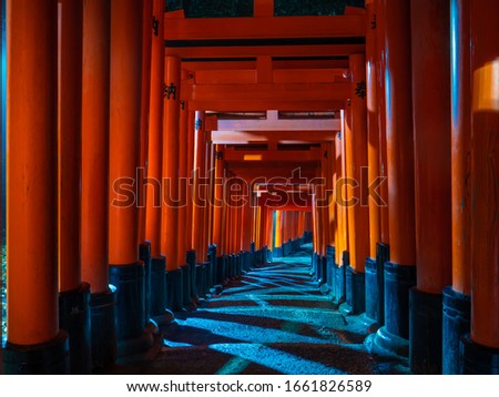 Famous gates way of Fushimi Inari Taisha in night time each gate has text translated to dedication