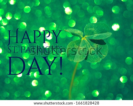 Happy St. Patricks day - inspirational motivation quote. Fresh green lucky four leaf clover on green sparkling background. Beautiful st patrick's day concept. Close up view, selective focus