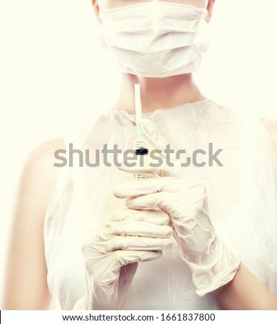 Nurse or surgeon woman doctor with syringe partial portrait. beautiful young woman in medical mask wearing gloves holding syringe
