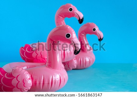 three inflatable pink flamingoes on blue background copy space
