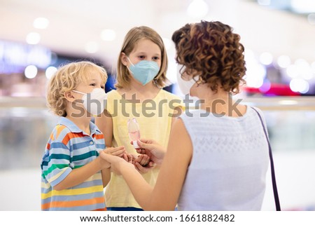 Family with kids in face mask in shopping mall or airport. Mother and child wear facemask during coronavirus and flu outbreak. Virus and illness protection, hand sanitizer in public crowded place. Royalty-Free Stock Photo #1661882482