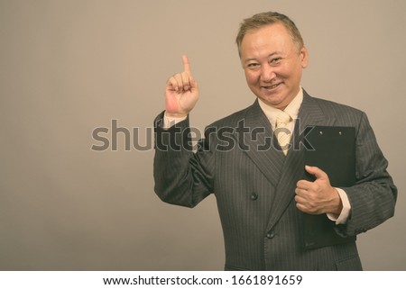 Portrait of mature Asian businessman with clipboard
