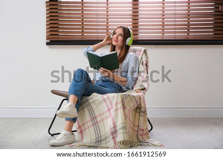 Woman listening to audiobook in chair at home