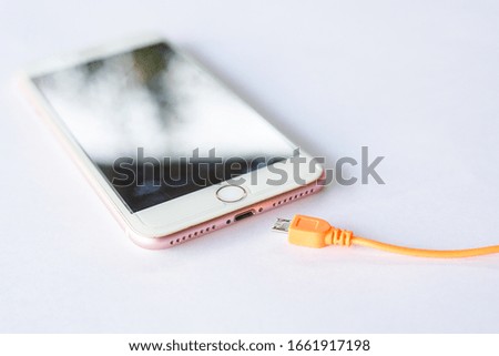 Smartphone that is ready to plug in the orange charging cable