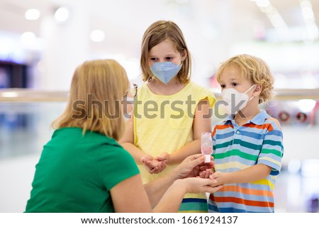 Family with kids in face mask in shopping mall or airport. Mother and child wear facemask during coronavirus and flu outbreak. Virus and illness protection, hand sanitizer in public crowded place. Royalty-Free Stock Photo #1661924137