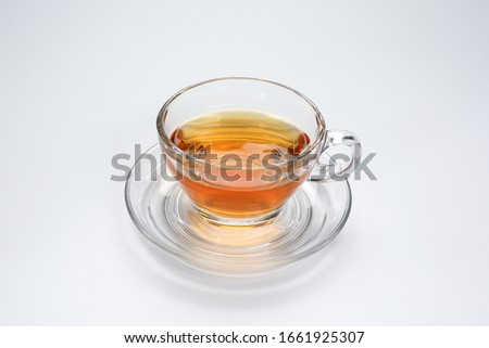Clear licker tea in a transparent glass cup saucer on white background 