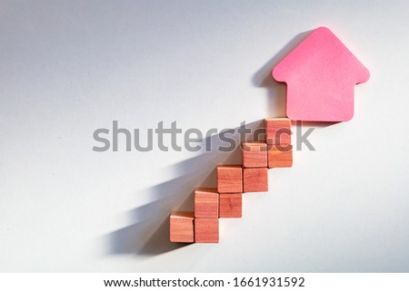 Rising graphic curve made with wooden boxes with house shape on the end. House budgeting