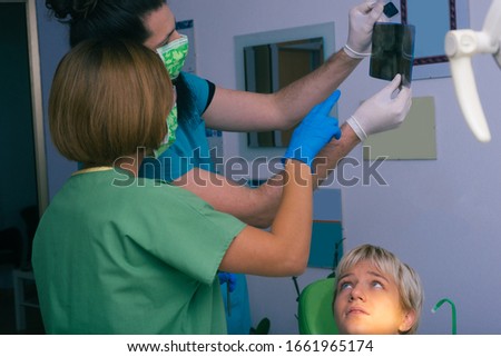 Male dentist showing the diagnosis of the x-ray picture to his colleague