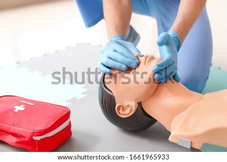 Instructor demonstrating CPR on mannequin at first aid training course Royalty-Free Stock Photo #1661965933