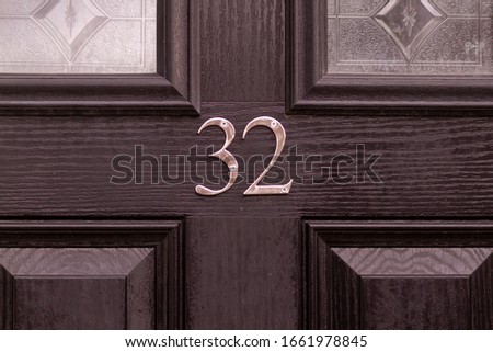 House number 32 on a black wooden front door