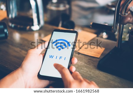 Woman hand using smartphone with wifi icon in public place outdoor background. Business communication social network concept. Royalty-Free Stock Photo #1661982568