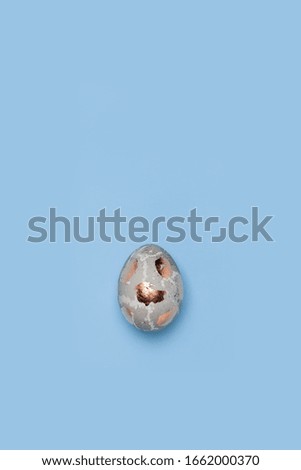 One gilded chicken egg on a blue background.