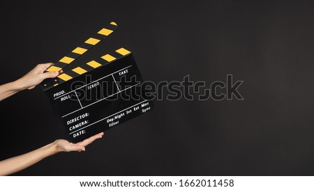 Hand's holding black Clapper board or clapperboard or movie slate use in video production and cinema industry on black background.