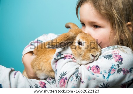 Child girl hug rabbit. Portrait of kid and bunny in hands. Easter surprise
